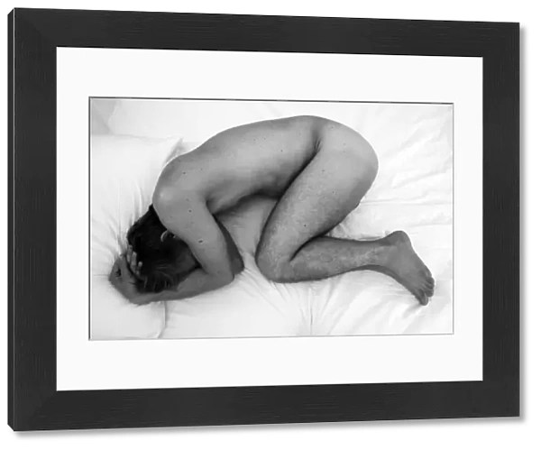 Nude study of man curled up into a ball