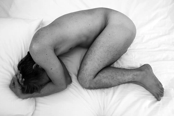 Nude study of man curled up into a ball